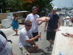 Displaying part of our catch: Grant, my brother in law on the left, Jon, my best man, in the center, and myself next to a pile of discarded fish parts 