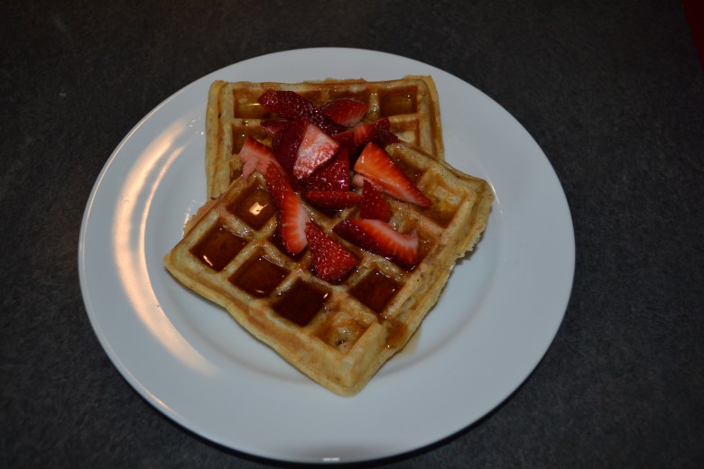 Whole wheat waffles with bourbon syrup and sliced strawberries 